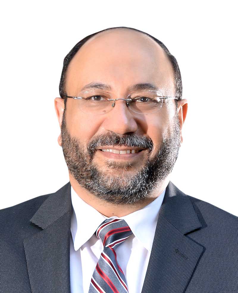 Sherif Hashem wears glasses with a dark suit and plaid tie for his faculty profile in the Department of Information Sciences and Technology.