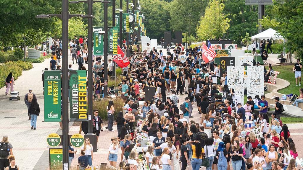 A large crowd of Mason students walk through campus