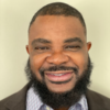 Elijah Bass, a black IST PhD student at Mason, has a beard and wears a gray suit and light shirt in his profile.