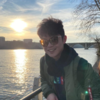 Hung-Mao Chen, IST PhD student at Mason, wears sunglasses, a black hoodie, and green jacket while standing on a pier.